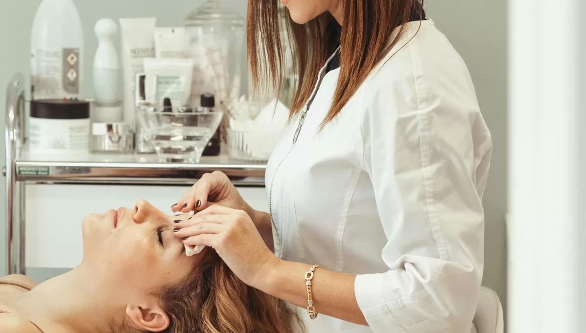Aesthetician cleansing a client’s skin during a facial treatment